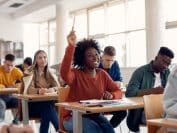 Une personne étudiante lève la main dans son cours universitaire